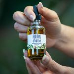 Close-up of hands holding a hair scalp oil bottle.